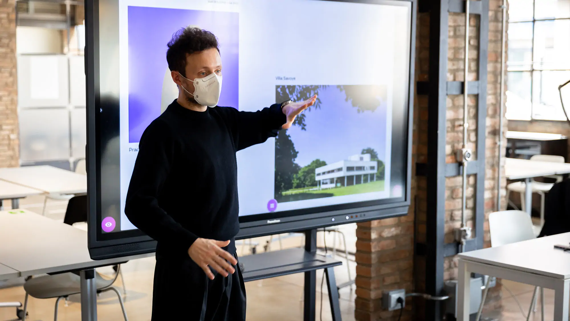 A professor during an Interior design lesson stands in front of a large screen at IAAD university